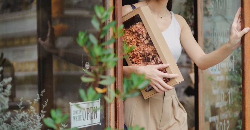 Gift - Crop glad woman with dried flowers box leaving floristry store