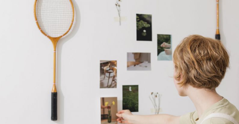 Decorating Ideas - Photo of a Redhead Woman Decorating a Wall with Photos and Tennis Rackets